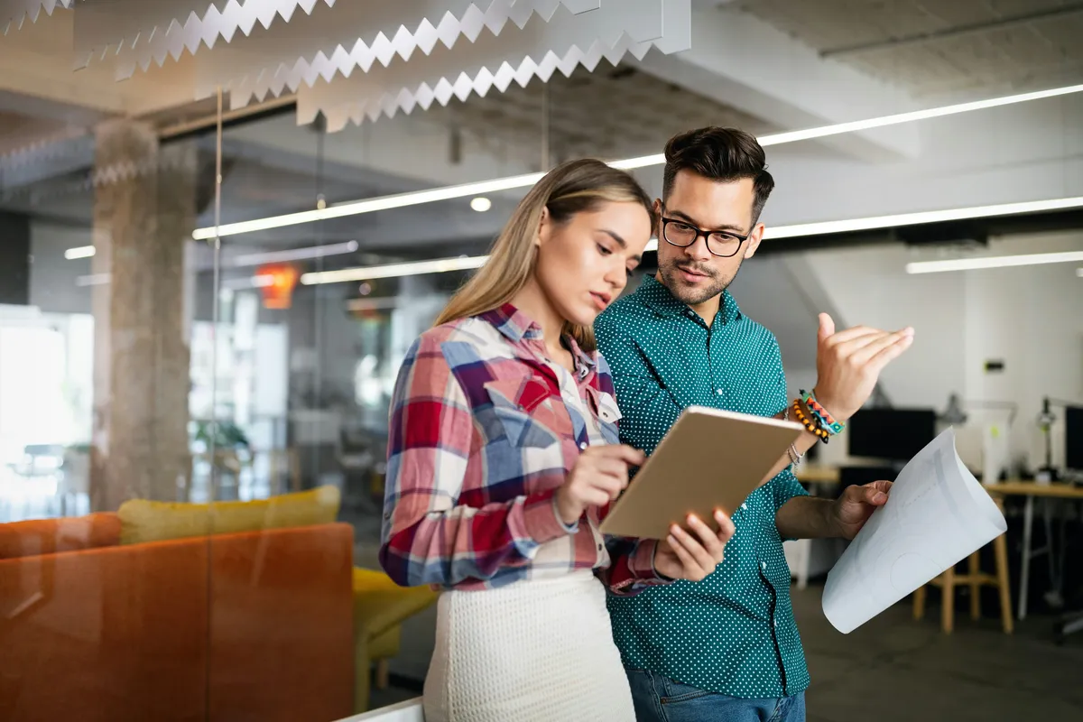 Une collègue présente des résultats à un gestionnaire dans un bureau moderne, représentant une démarche d’évaluation psychométrique RH.